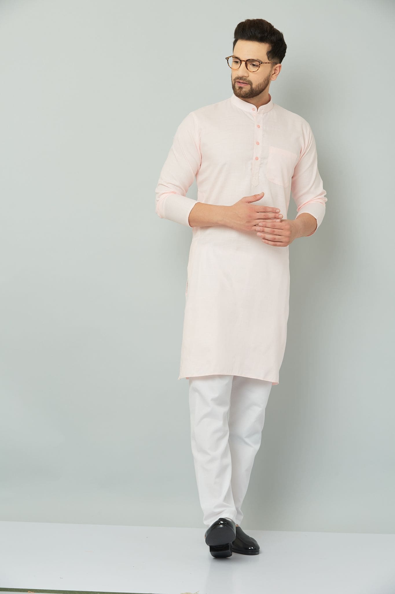 Man wearing a pink kurta and white pants.